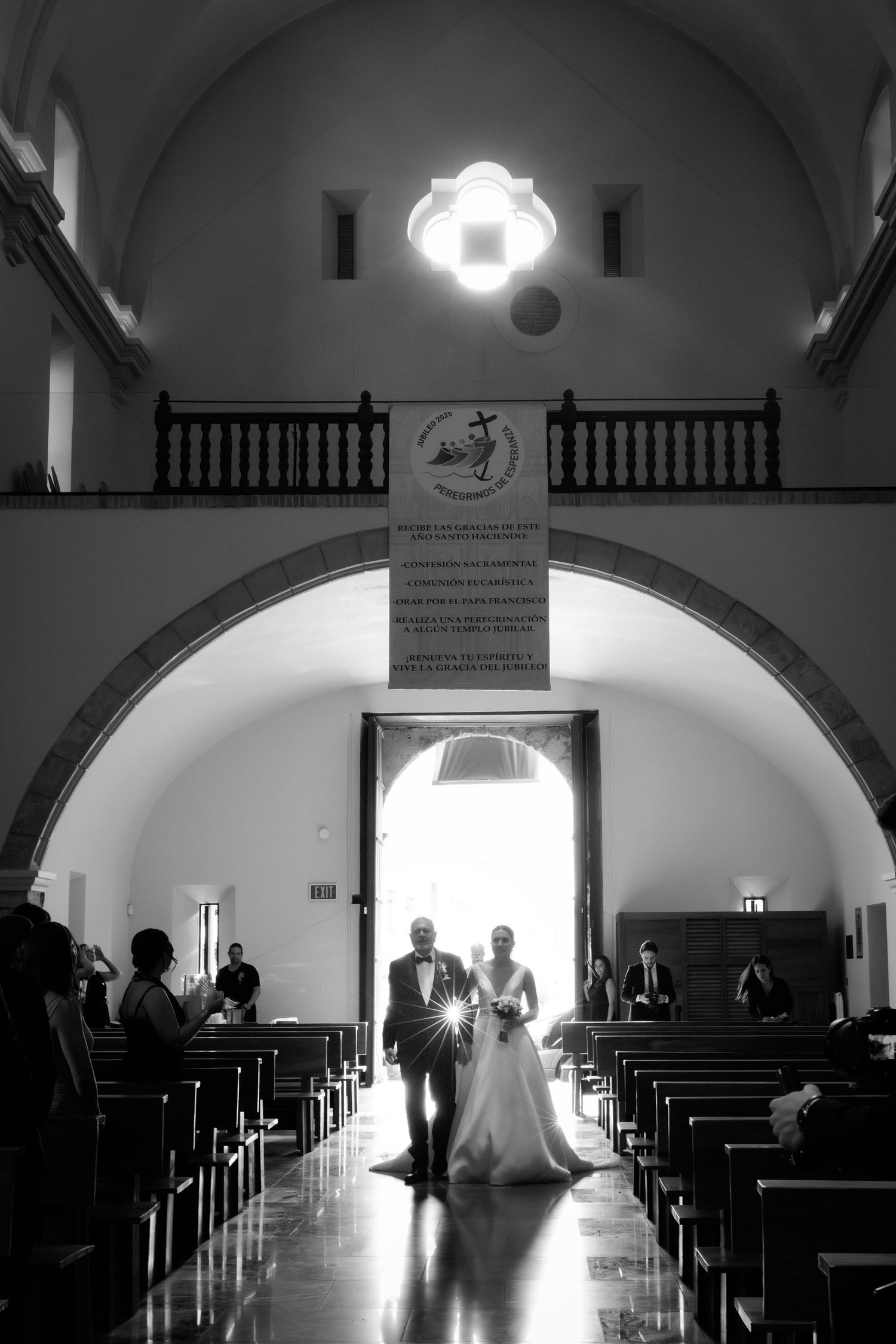 Dramatic black and white wedding ceremony silhouettes inside a church with arched ceilings and pews.