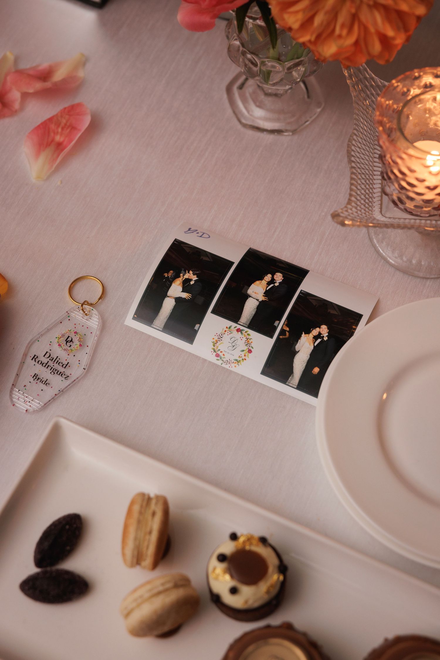 Wedding reception details with photo prints, desserts and romantic decor on a white tablecloth.