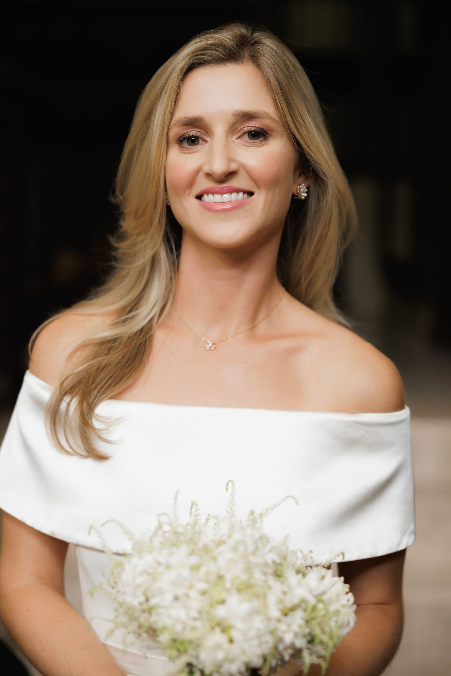 Close-up portraits of a bride in an off-shoulder white wedding dress holding a delicate white floral bouquet.