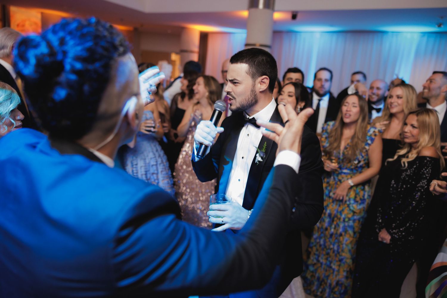 People dancing and celebrating at an elegant formal event with dramatic blue lighting and festive atmosphere.