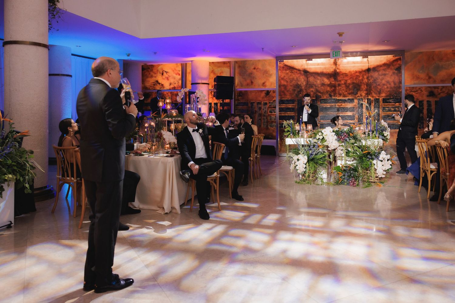 Formal event reception venue with blue uplighting and patterned floor lighting effects.
