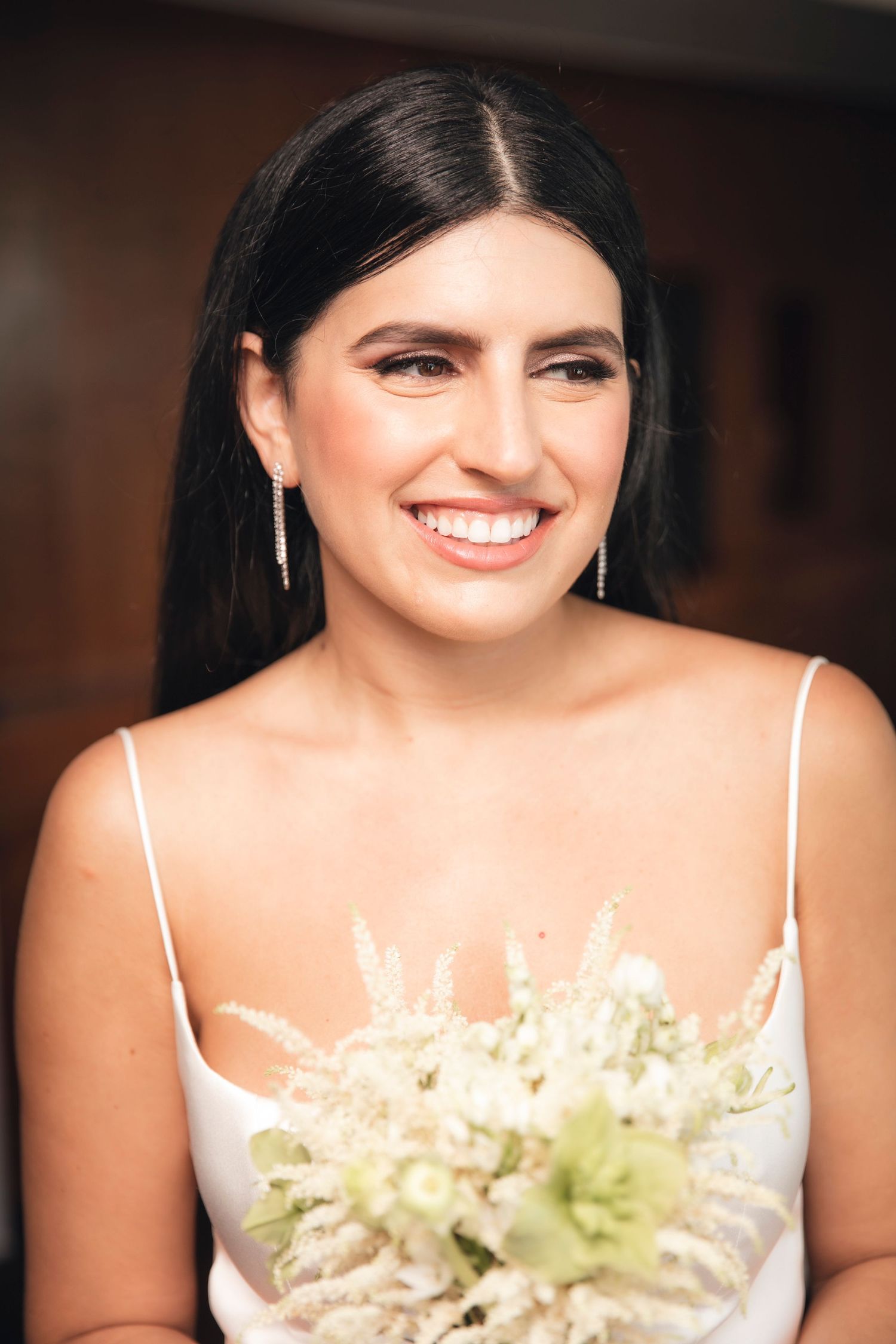 Portrait series showing varying expressions in white dress with delicate floral bouquet against dark background.