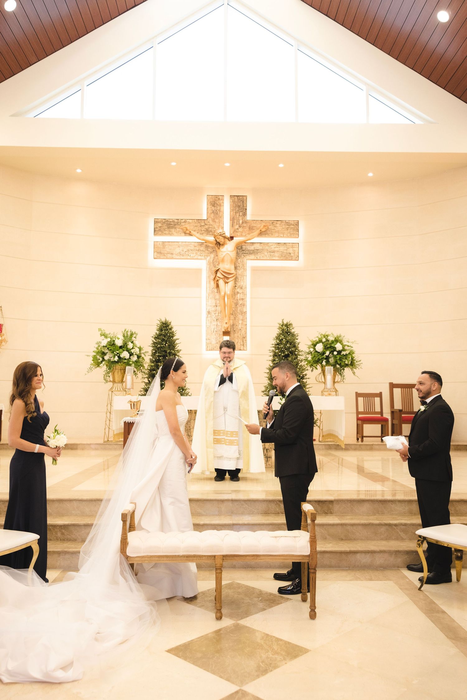 Church wedding ceremony inside a modern chapel with white interior and wood beam ceiling.