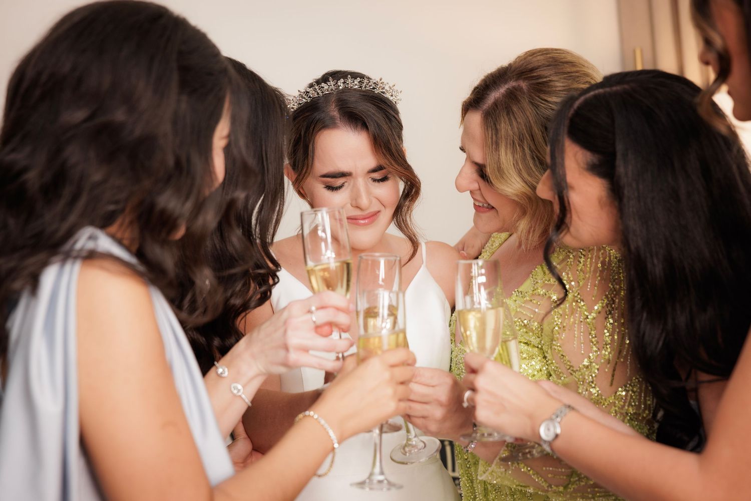 Group of friends in formal attire laughing and raising champagne glasses in celebration.