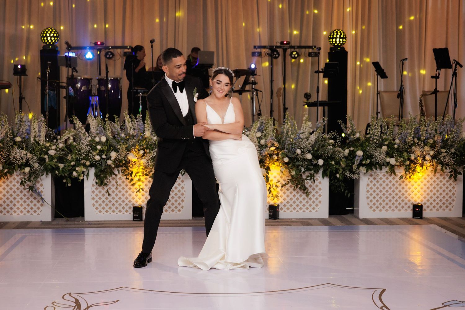 A couple shares their first dance at an elegant wedding reception with floral decor and candlelight.