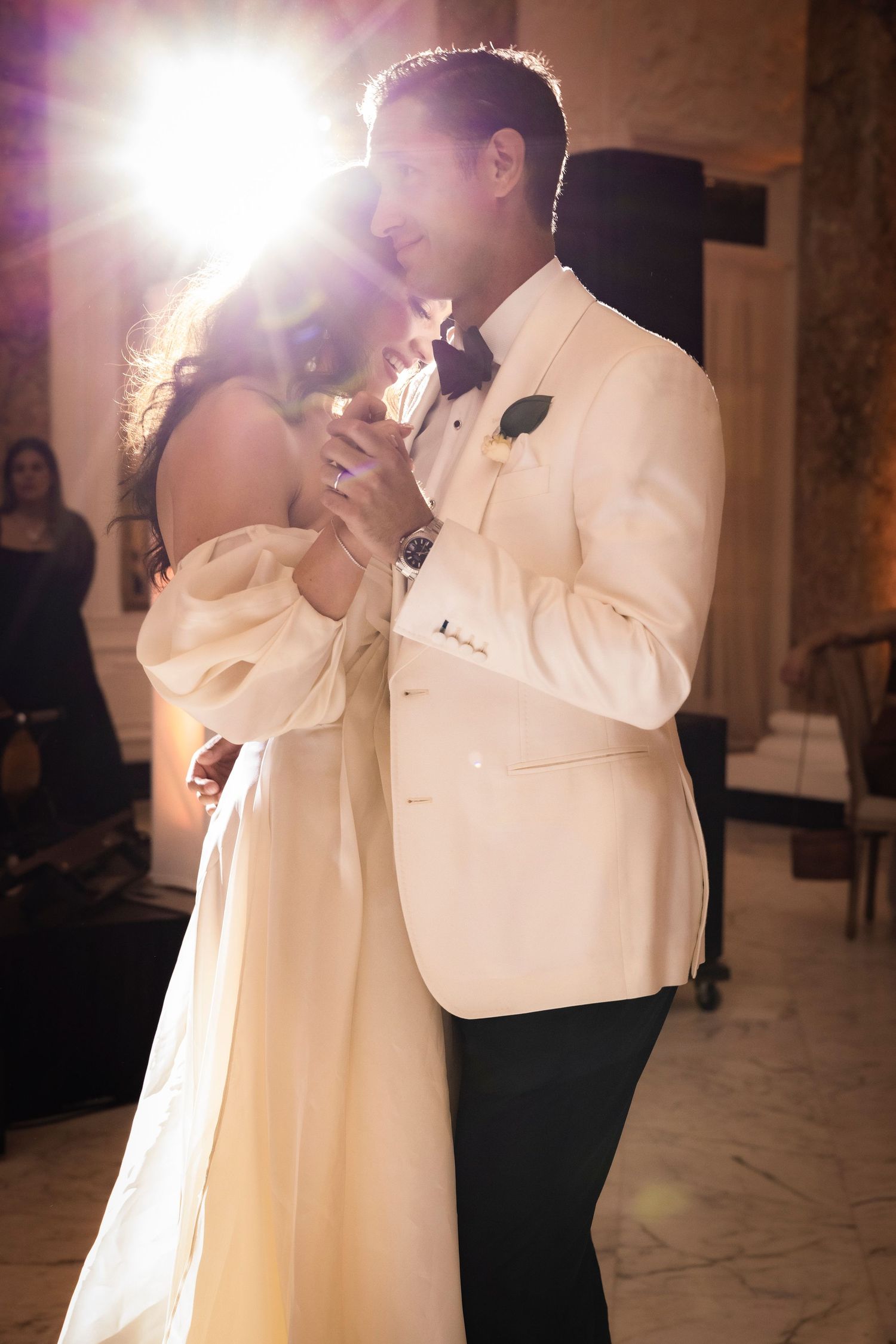 An emotional first dance moment captured in dramatic lighting at an elegant wedding reception.