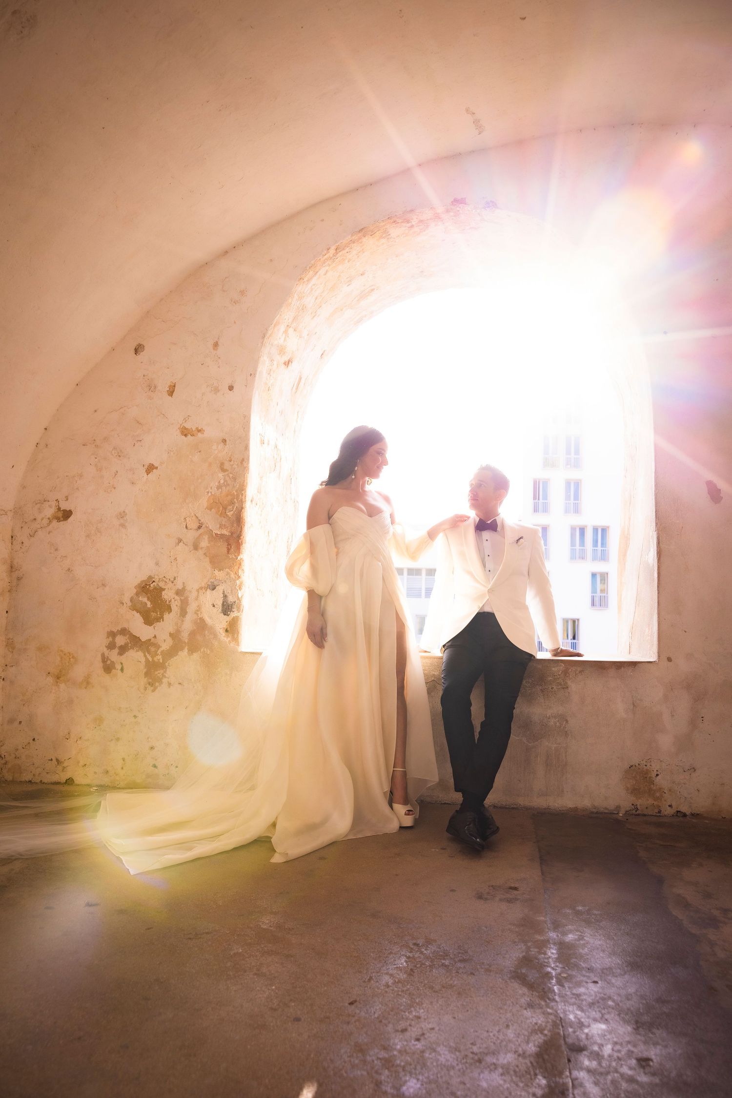 Sunlight streams through windows in a rustic stone room during a wedding photoshoot.