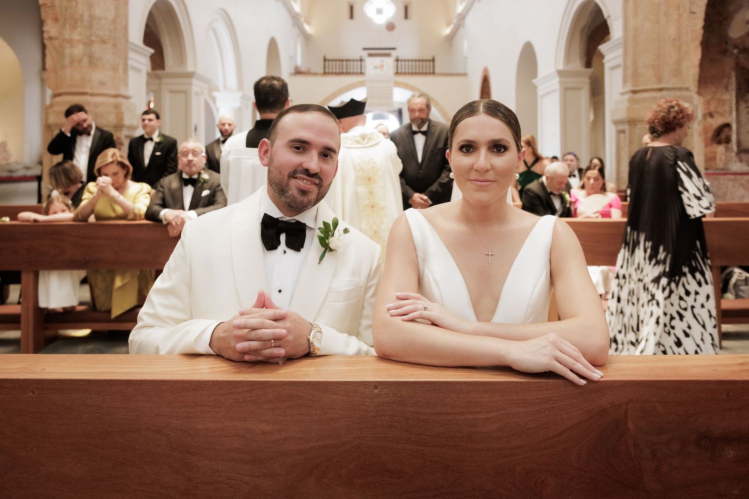 Wedding reception scene in church hall with guests seated at long tables.
