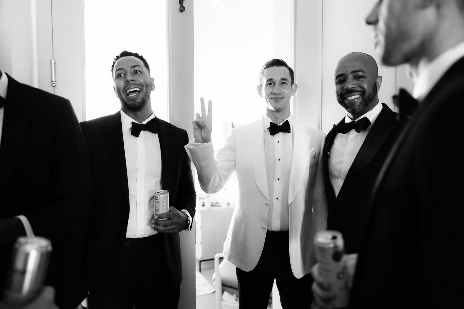 A black and white collage of groomsmen laughing and smiling in formal tuxedos and bow ties at a wedding.