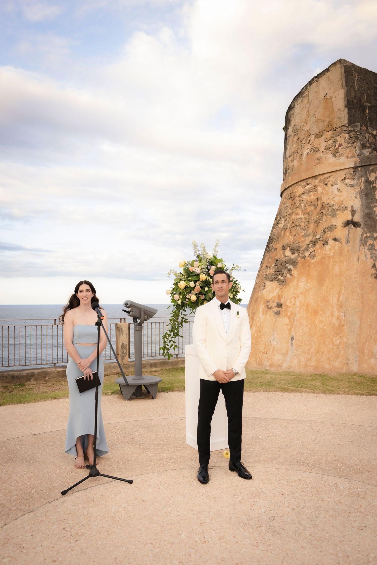 Outdoor wedding photos taken near historic stone fortress with ocean views.