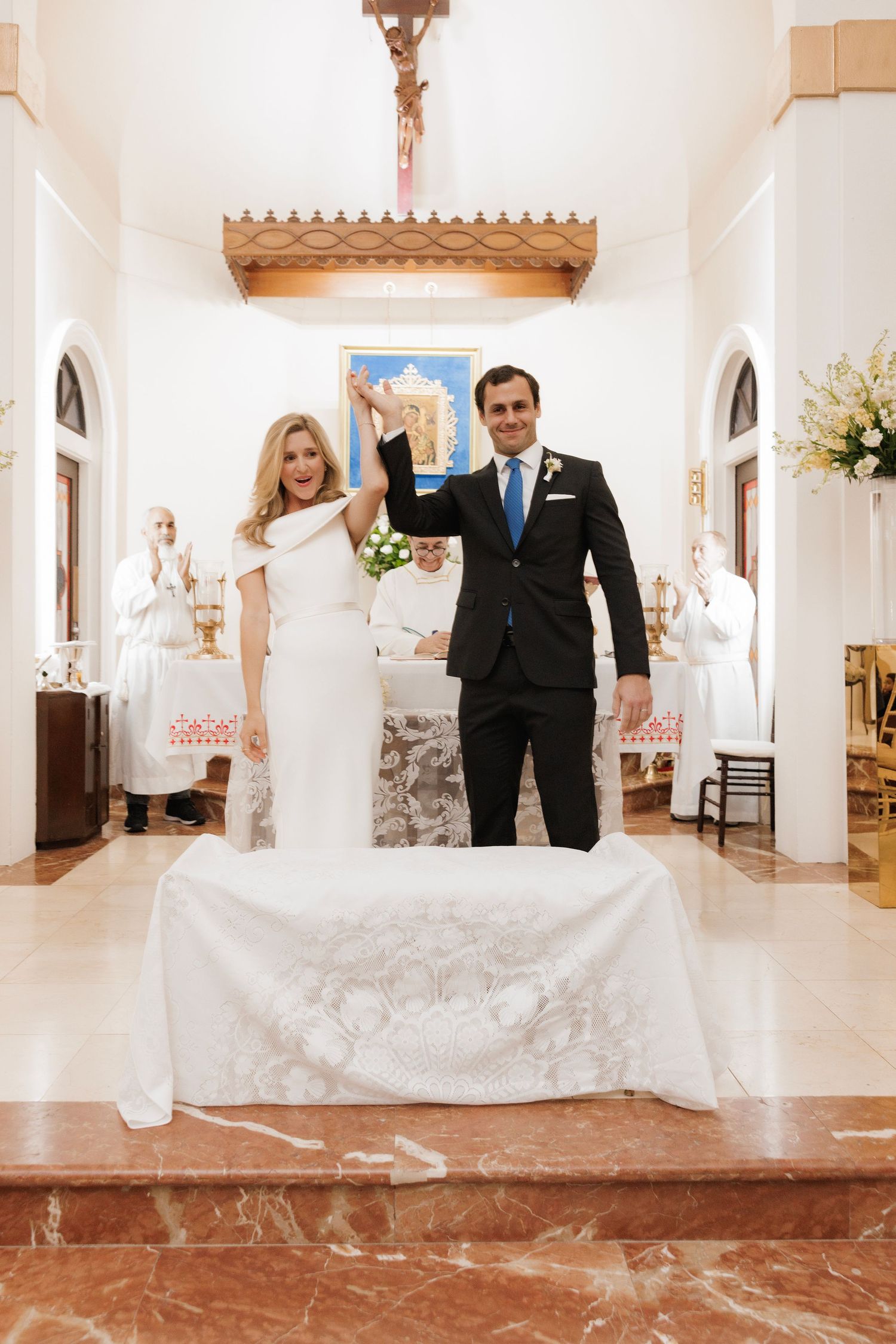 Wedding couple poses in a bright hallway with white columns and terracotta tile floors at their elegant venue.