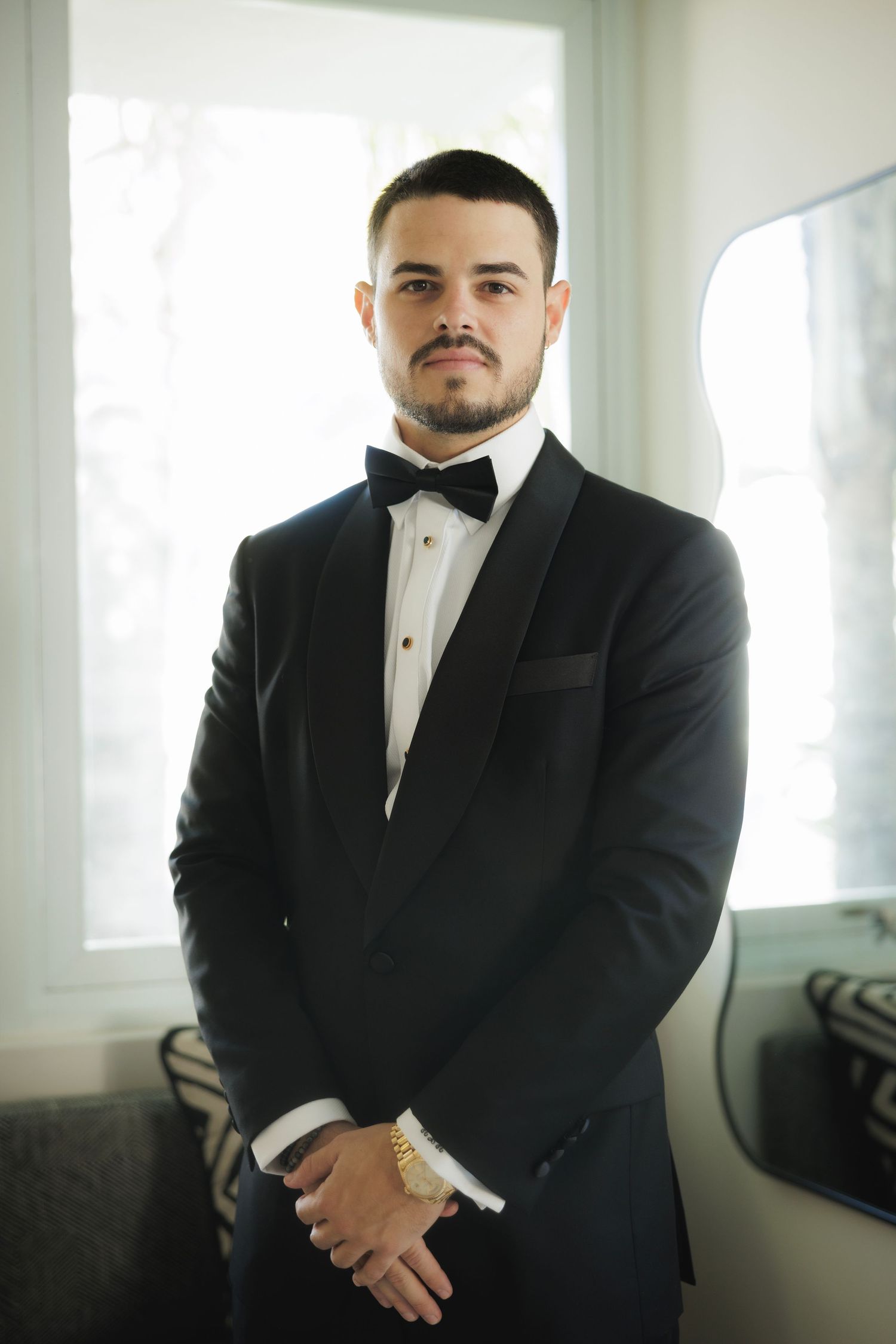 Formal portrait of someone wearing a classic black tuxedo with bow tie.