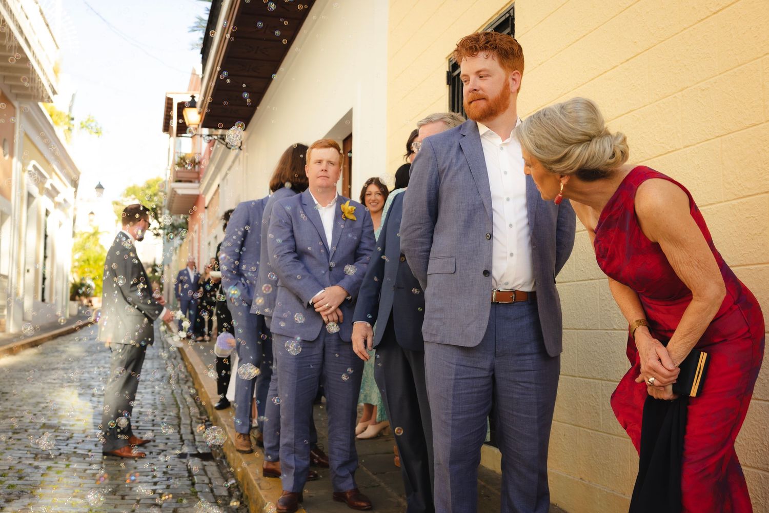 Small sequential wedding gathering images showing a group walking through hallways wearing blue suits and red dresses.
