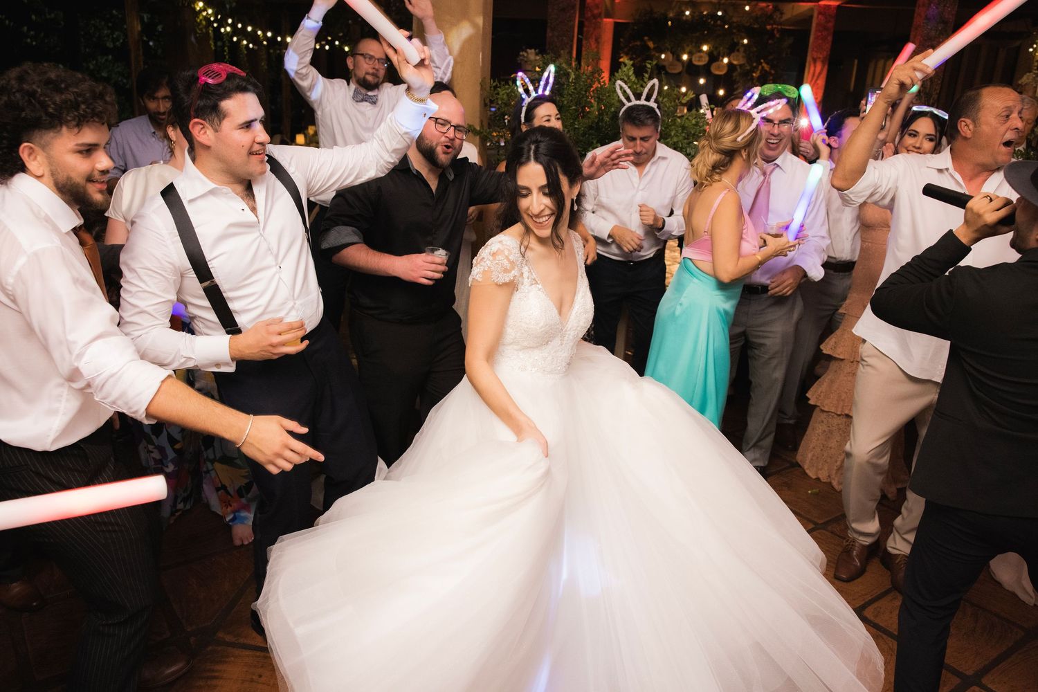 Wedding guests performing choreographed dance moves on the reception dance floor under glittering lights.