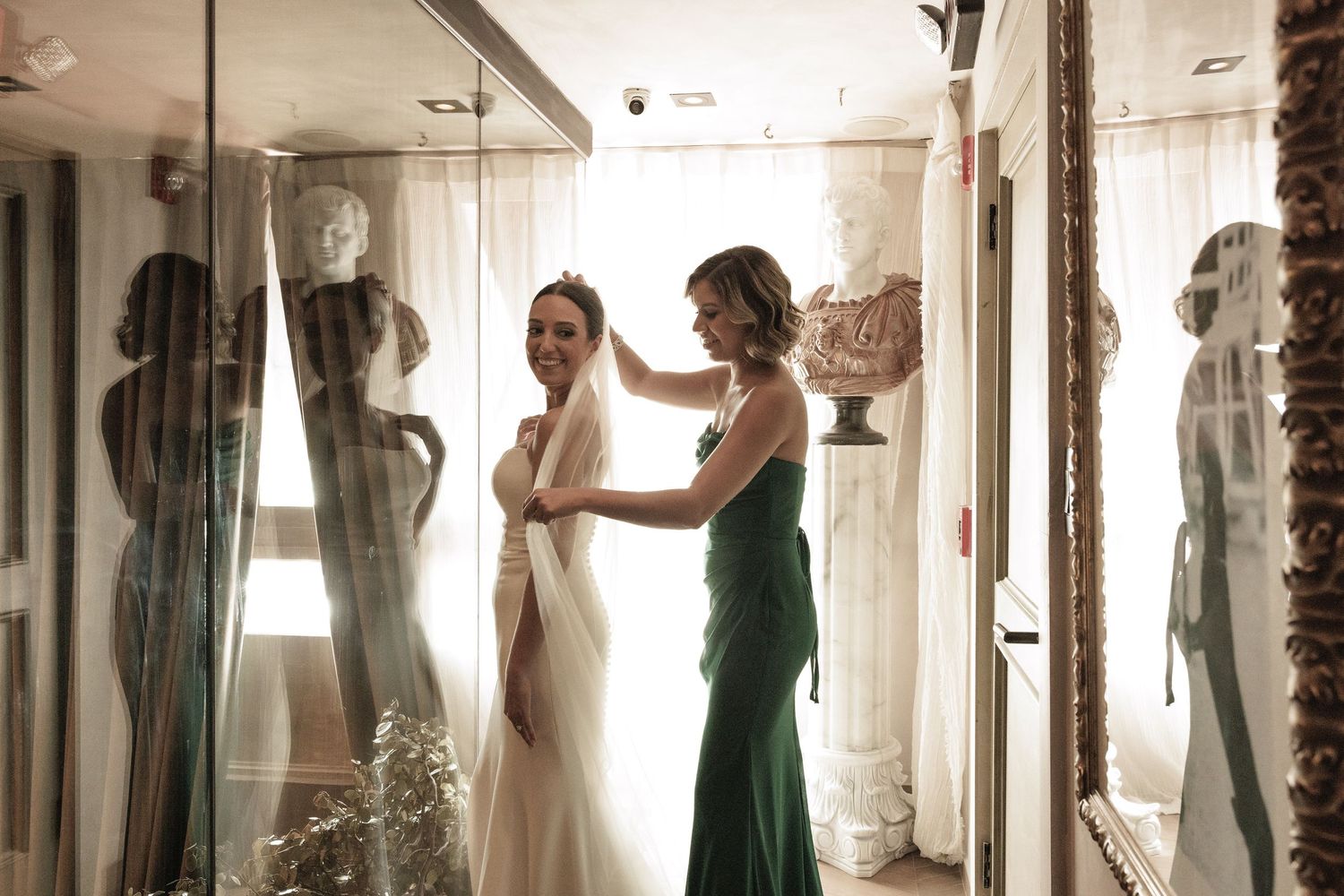 Wedding preparation scene reflected in multiple mirrors showing dress and preparations in soft light.