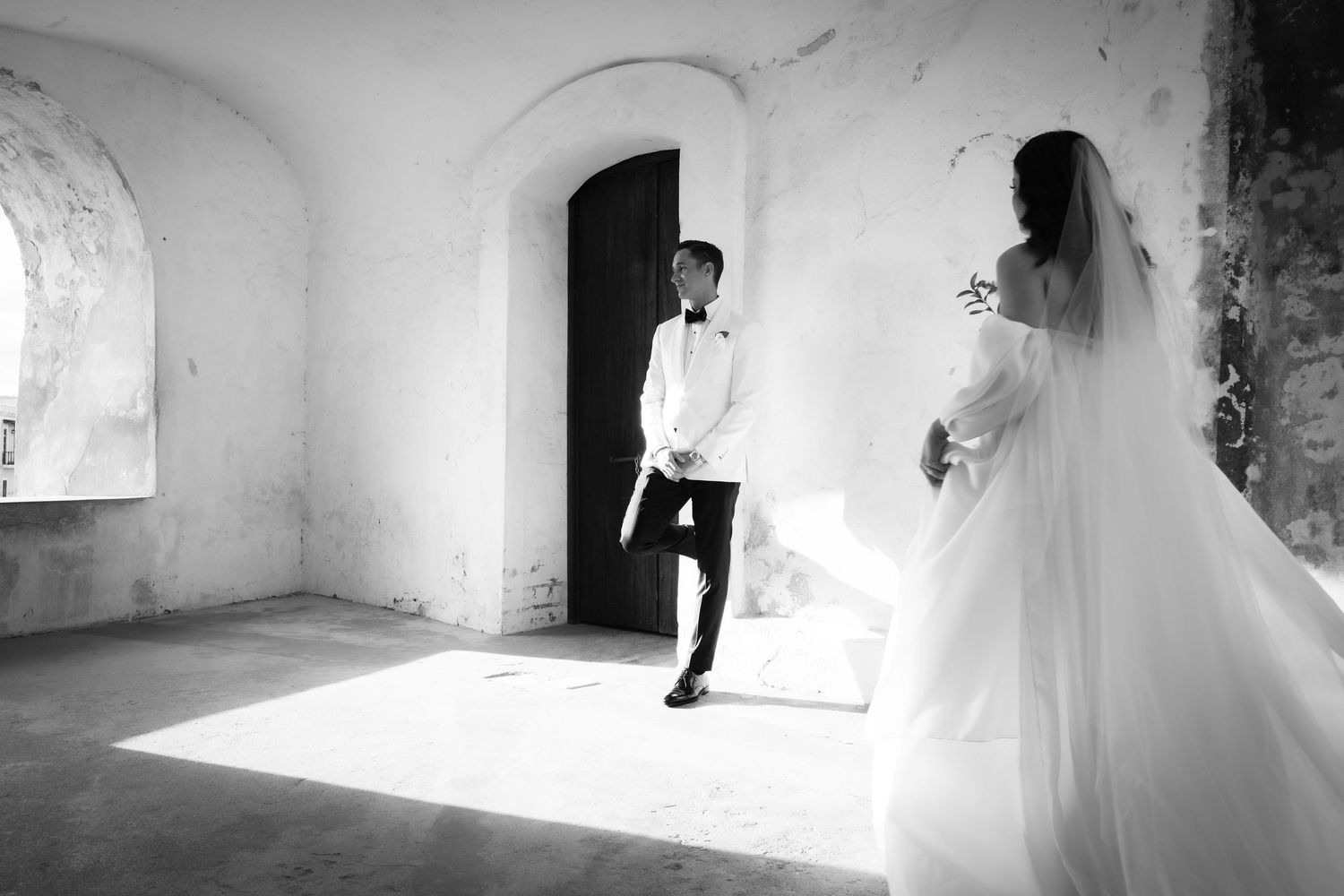 Artistic black and white wedding photos capture romantic moments in stone corridor.