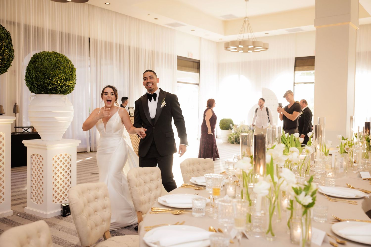 A gallery wall displays multiple framed photos in sequence at an elegant venue during a wedding reception.