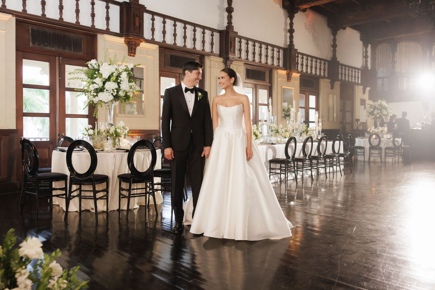 An elegant indoor wedding ceremony setup with wooden chairs and floral arrangements in a grand hall.