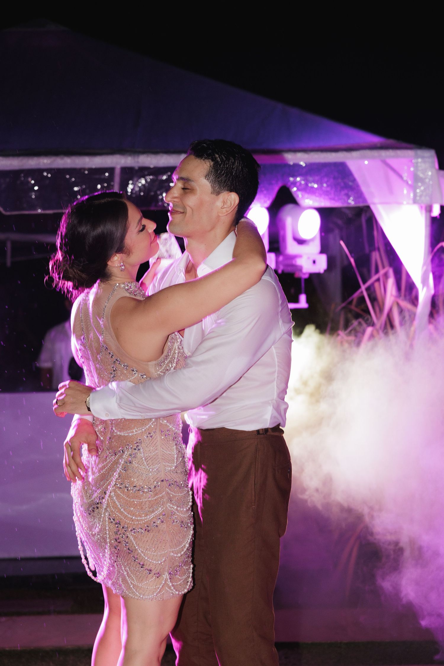 Couple dancing romantically in fog effects with purple ambient lighting at an indoor venue.