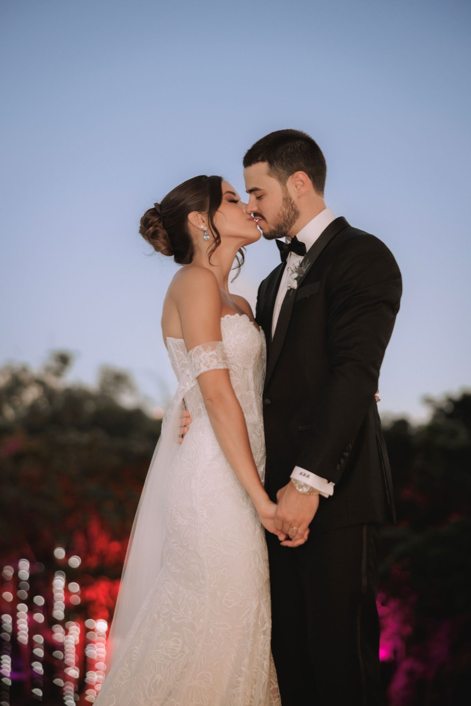 Romantic sunset wedding portrait with soft bokeh lights in background.