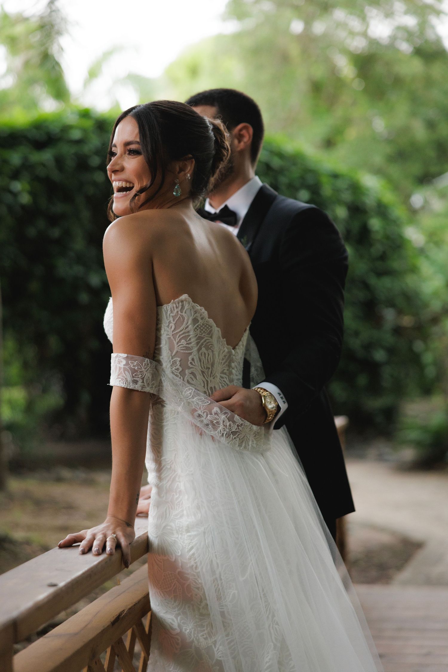 Wedding couple shares joyful moment together on outdoor garden pathway.