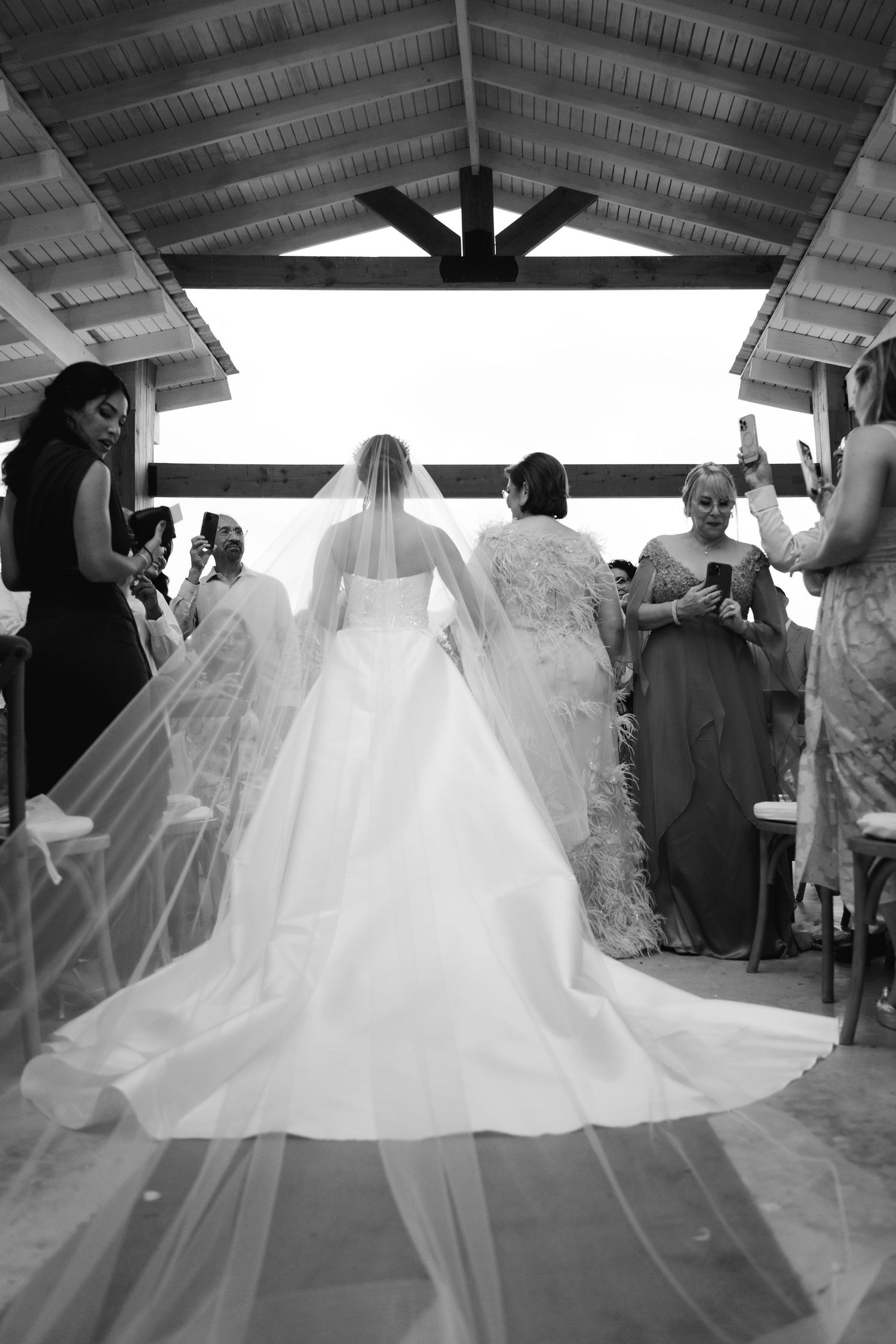 A flowing white wedding dress captured in a series of silhouettes against a covered outdoor venue.