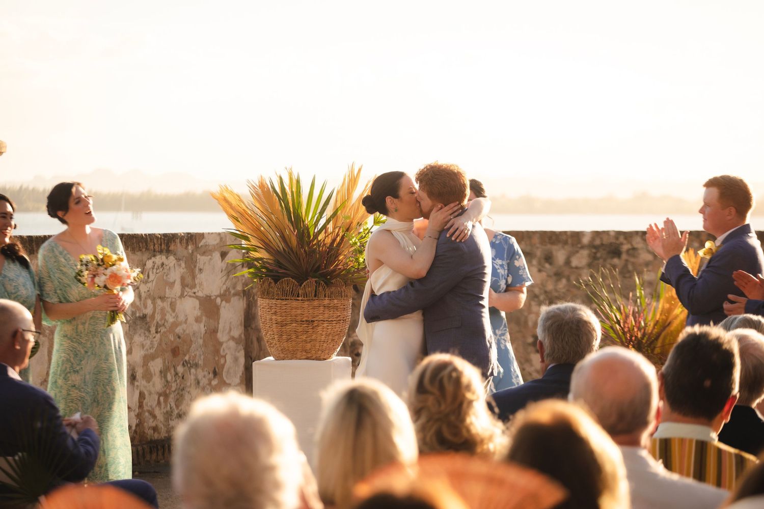 Wedding ceremony guests seated outdoors at a scenic venue during golden hour.