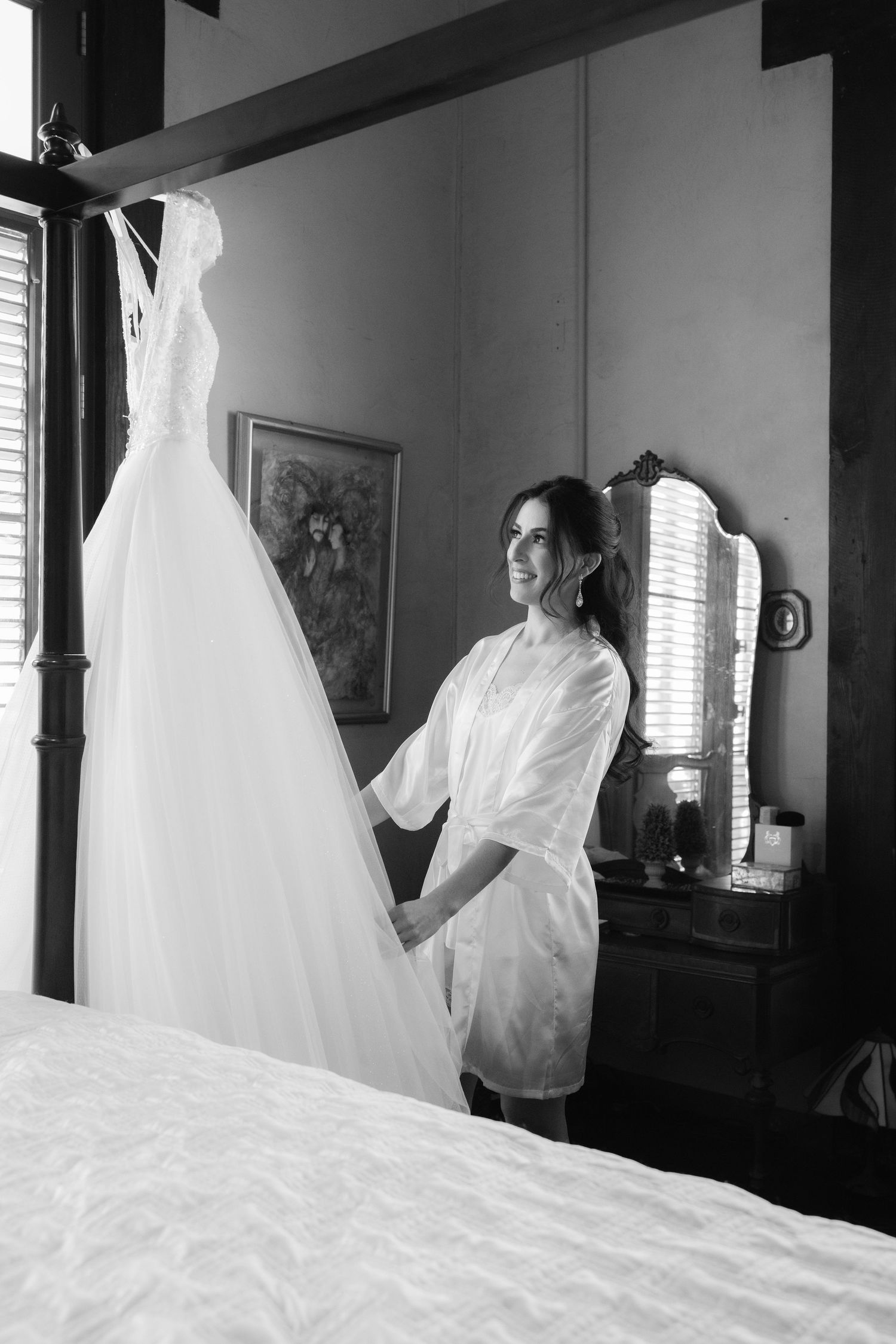 A sequence of four monochrome images showing a flowing white wedding dress being adjusted in a dimly lit room.