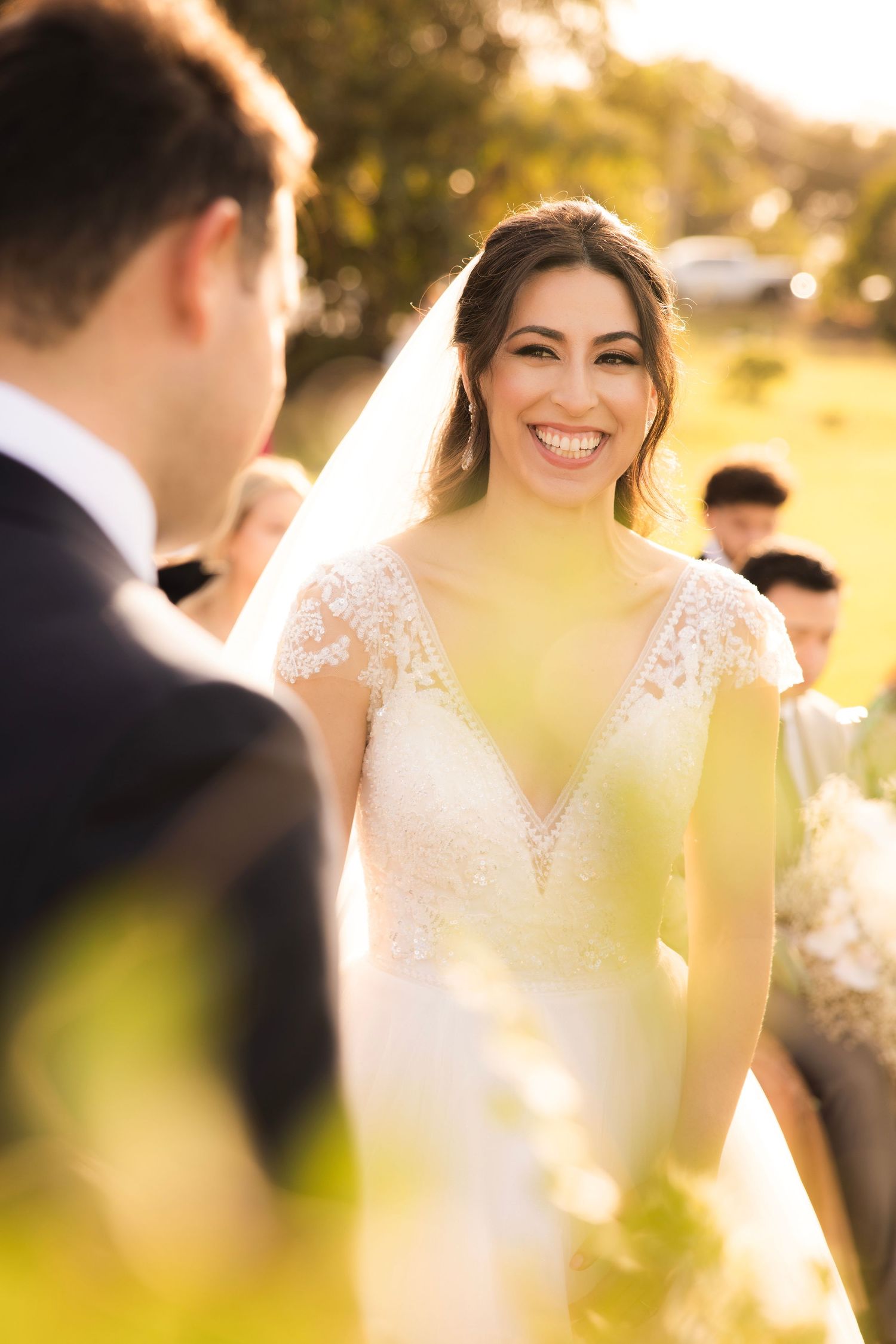 Outdoor wedding ceremony during sunset with soft golden lighting and guests.
