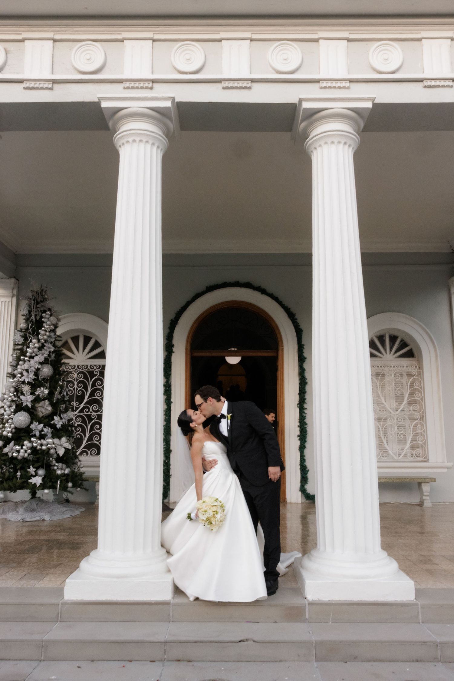 Romantic wedding moment captured on classic white columned porch.