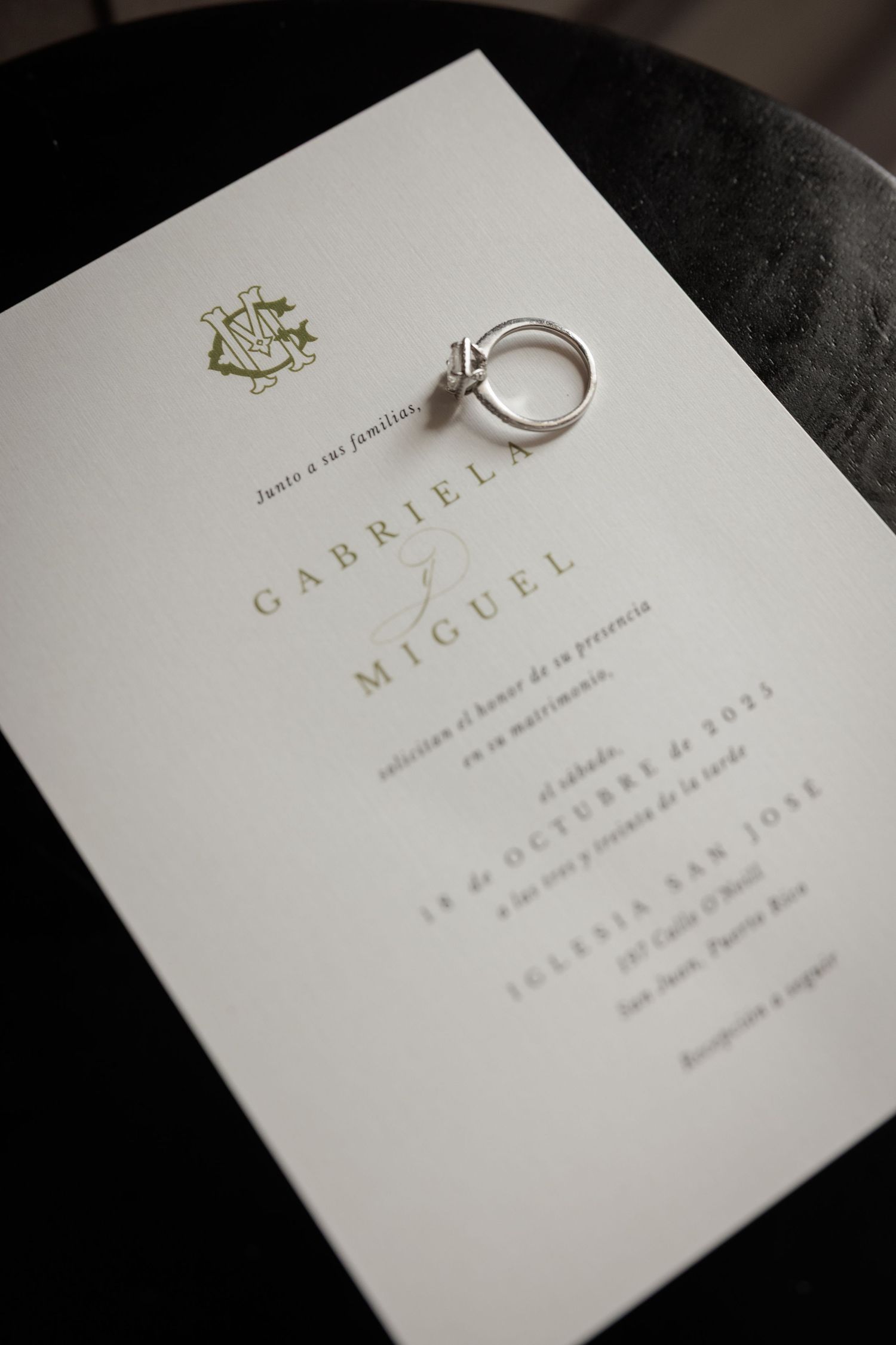 Wedding invitation cards with gold text and rings displayed on dark surface.