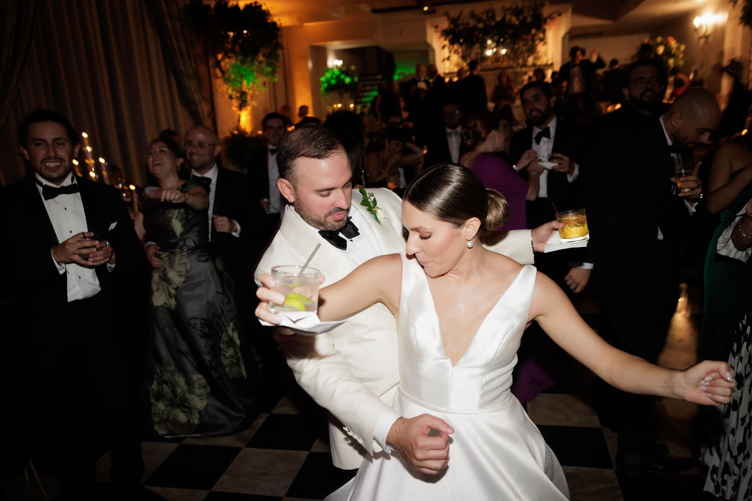 Guests dancing and celebrating at an elegant wedding reception with dimmed lighting and festive atmosphere.