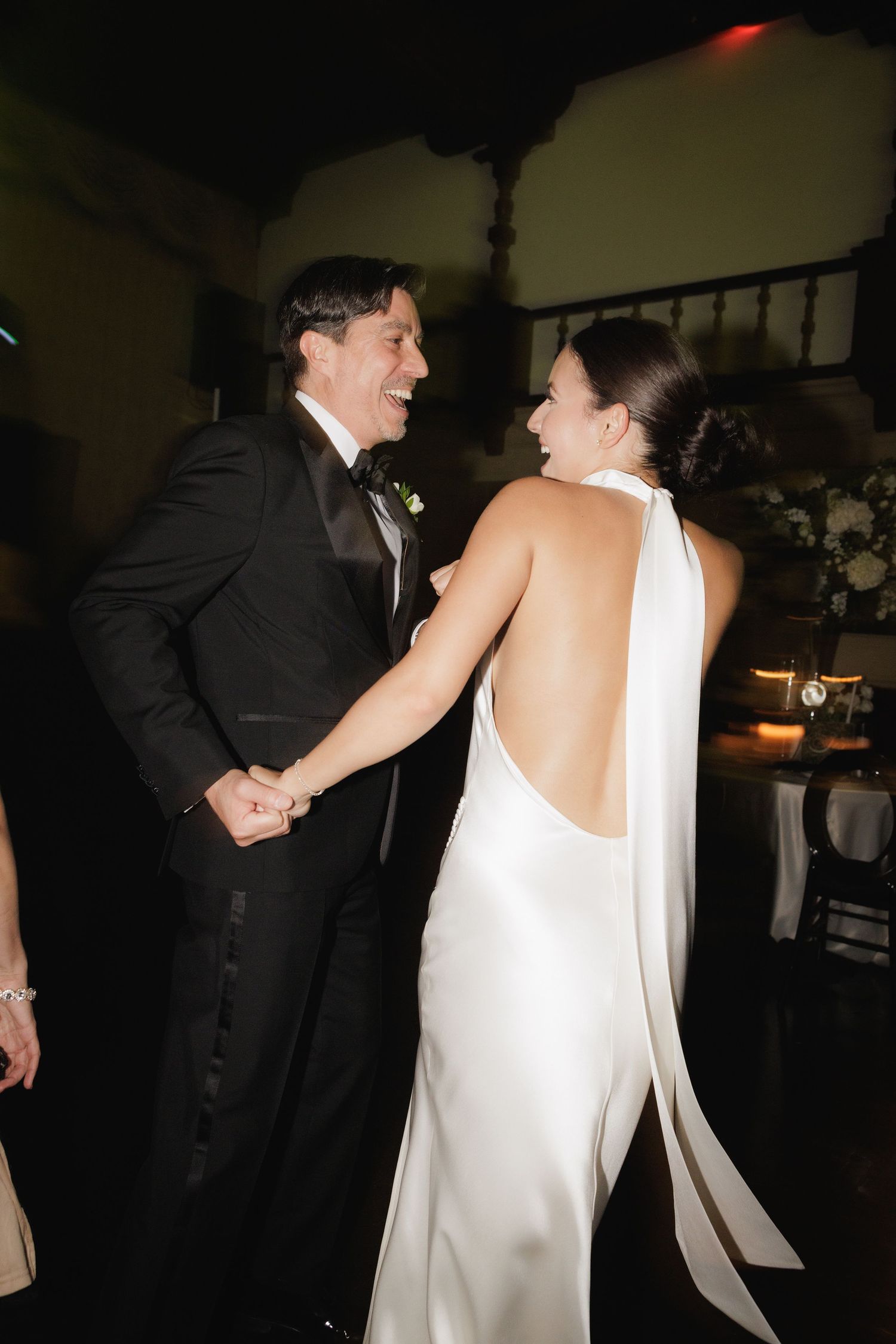 Couple shares intimate dance moves in dramatic low-light reception setting.