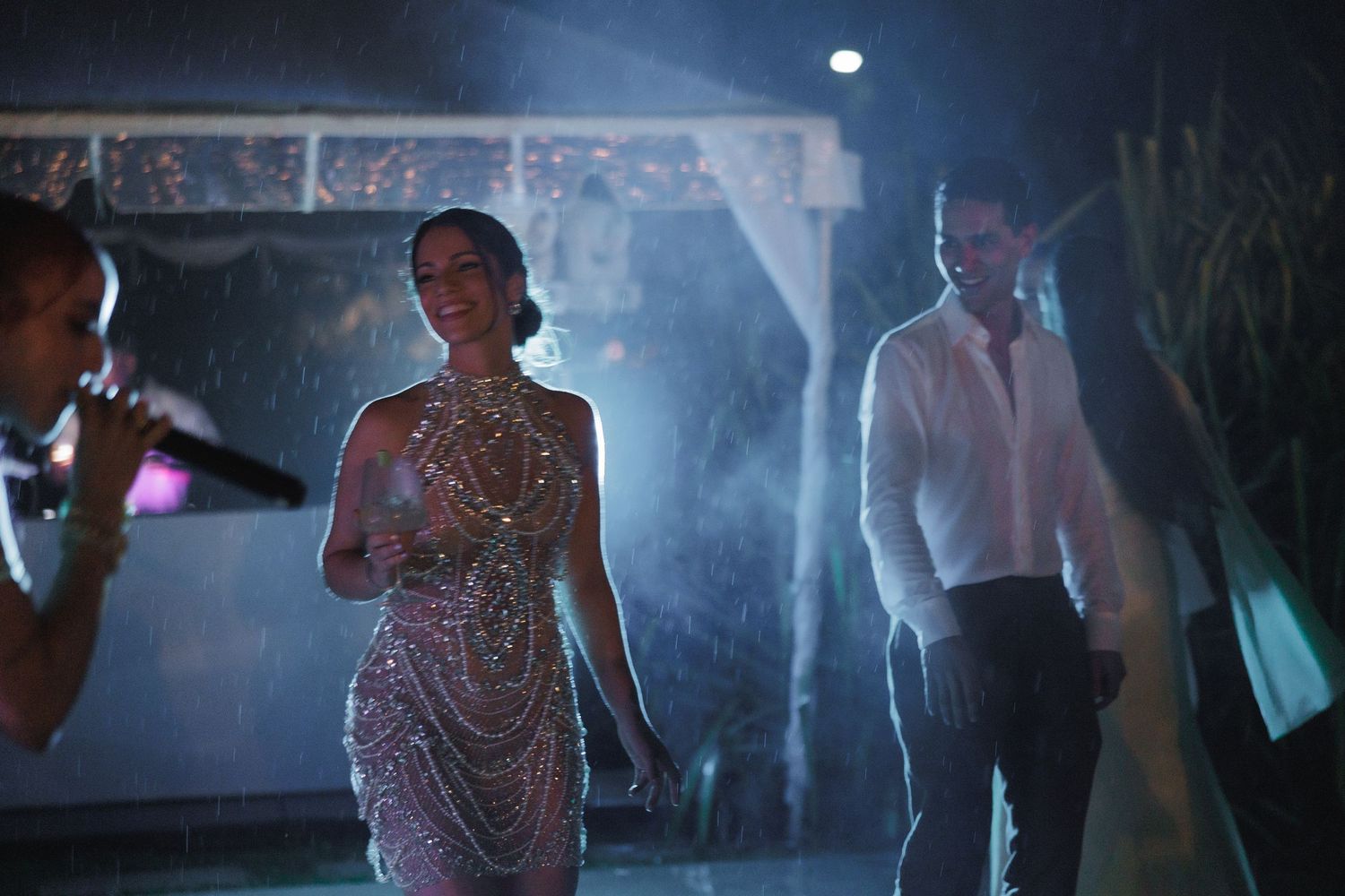 Silhouettes of party guests dancing under atmospheric blue lighting at a nighttime event.