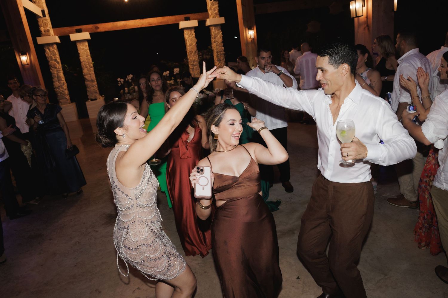 People dancing together at a lively wedding reception party with warm lighting and festive atmosphere.