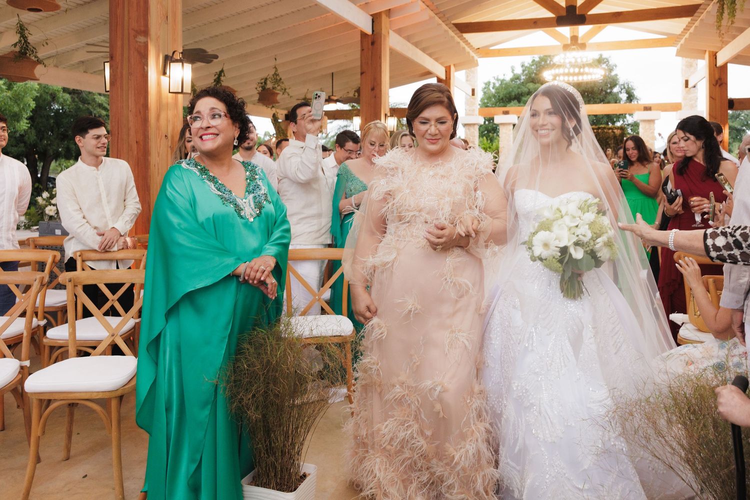 A wedding party celebrates with joyful dancing and laughter at an elegant covered outdoor reception venue.