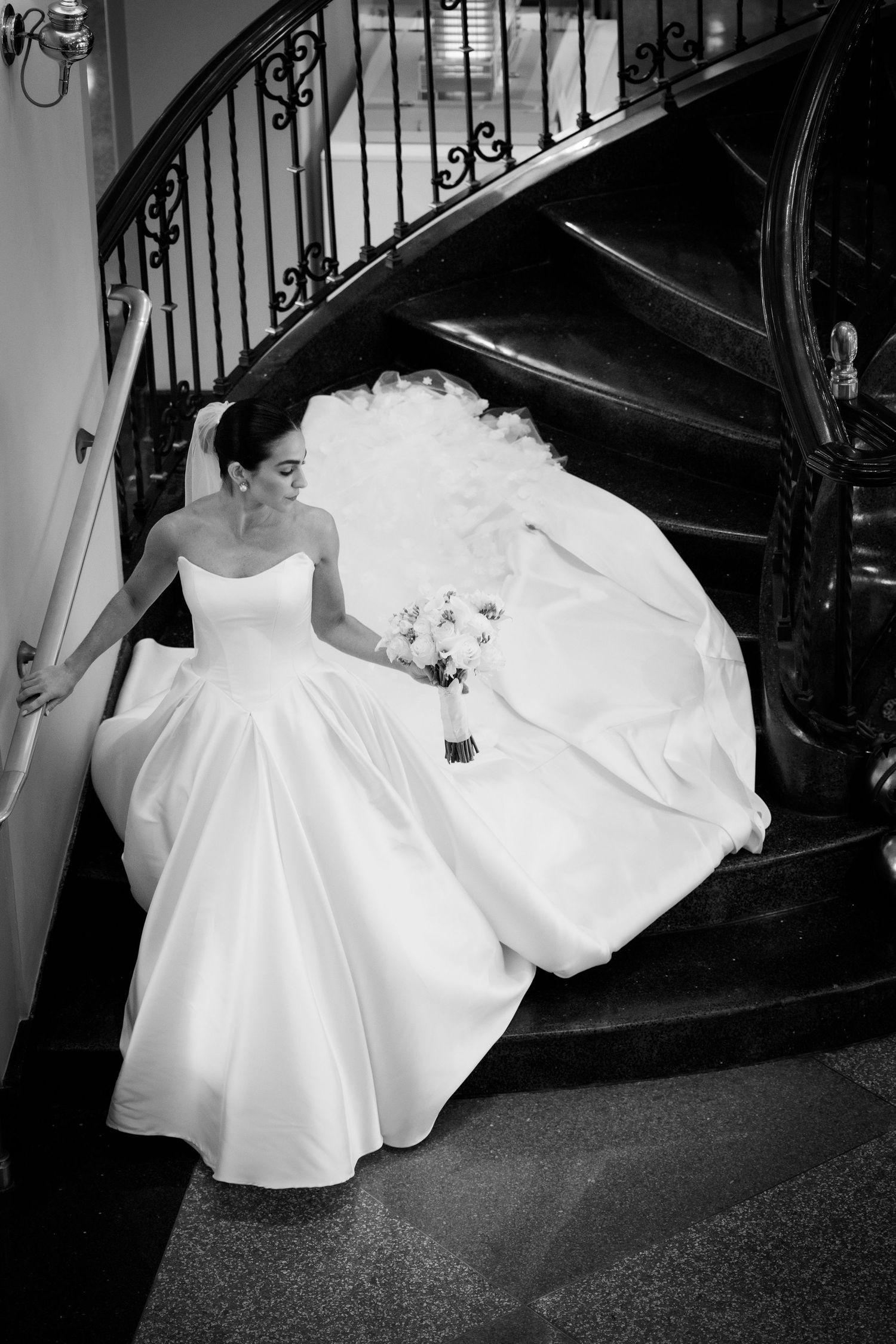 Black and white photo series showing flowing white wedding dress movement on a grand staircase.