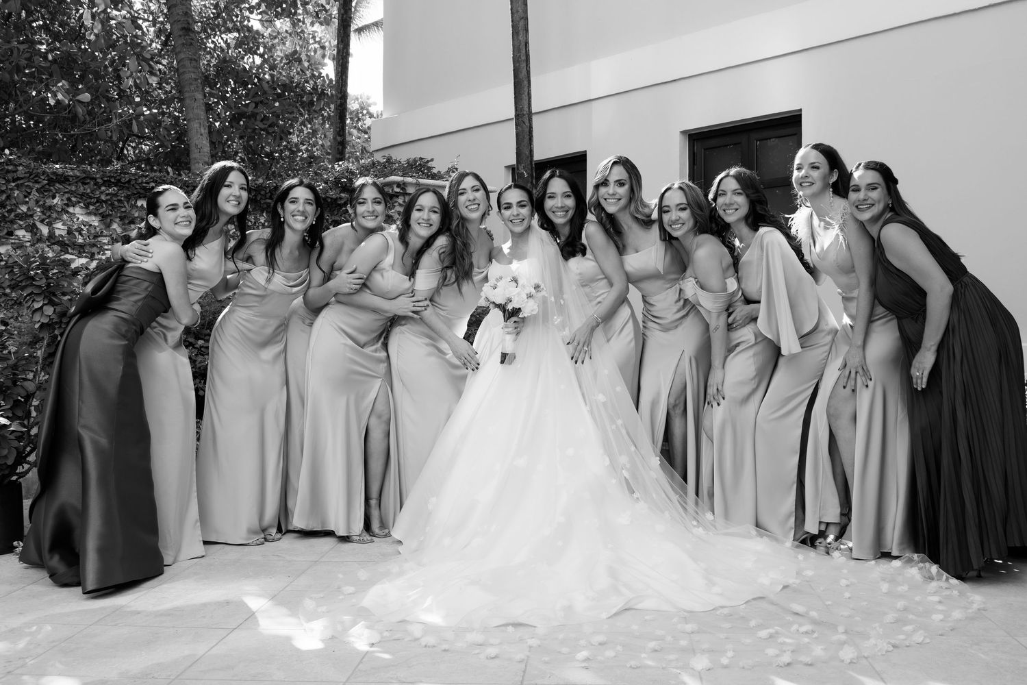 Wedding party in coordinated gray dresses posed together for a group photo outdoors.