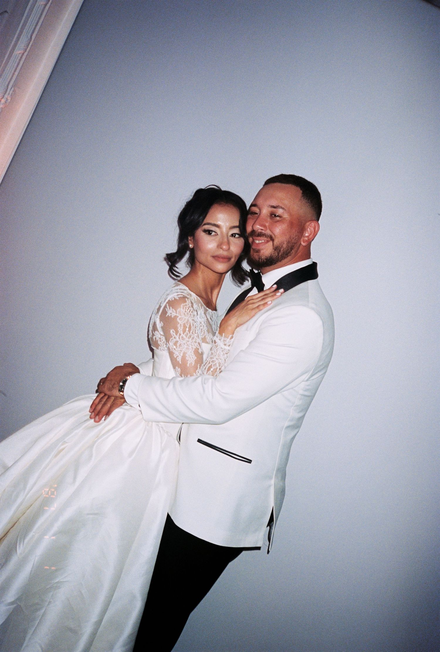 Bride and groom in matching white wedding attire posing together.