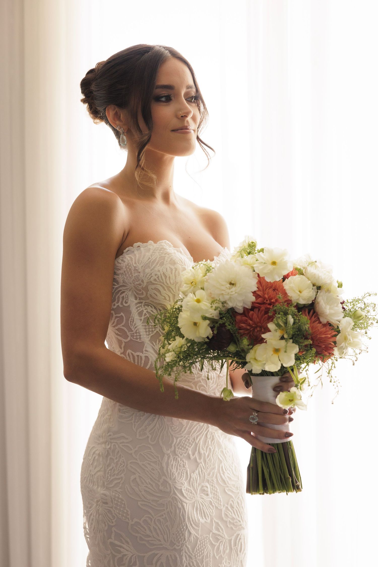 White wedding dress with beautiful bouquet of white and pink flowers in natural window light.