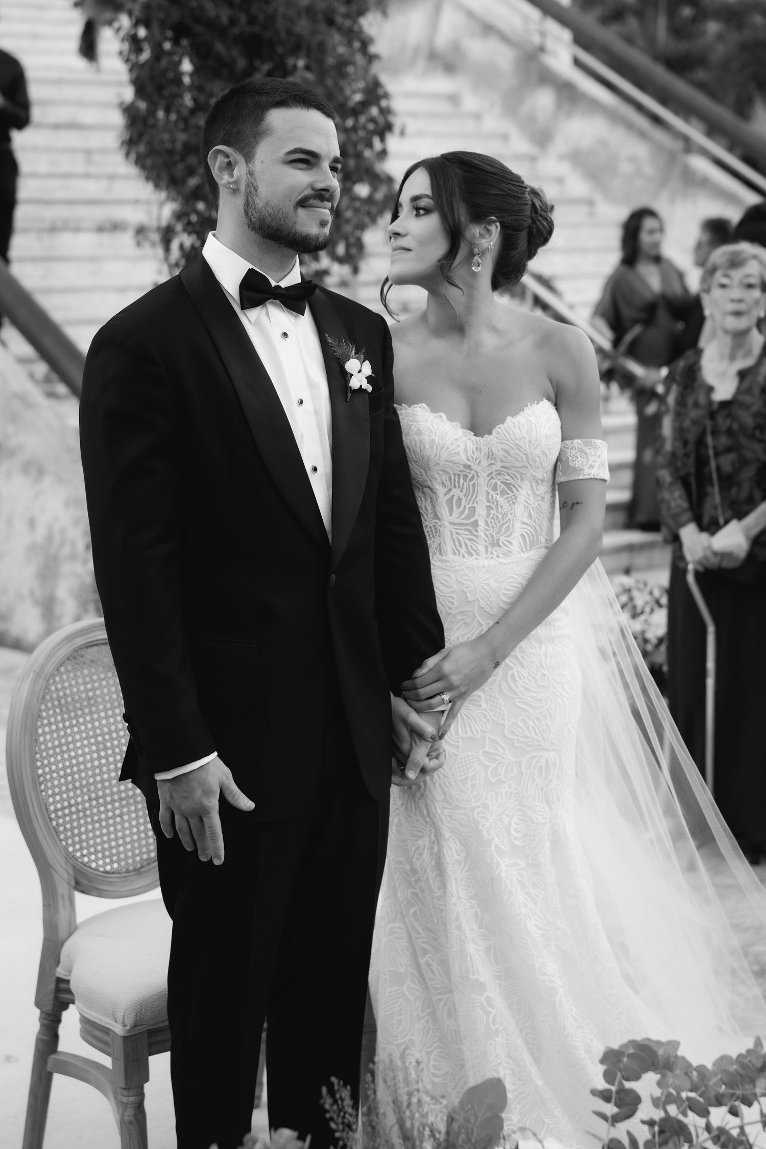 Black and white wedding moment captured against architectural backdrop with elegant attire.