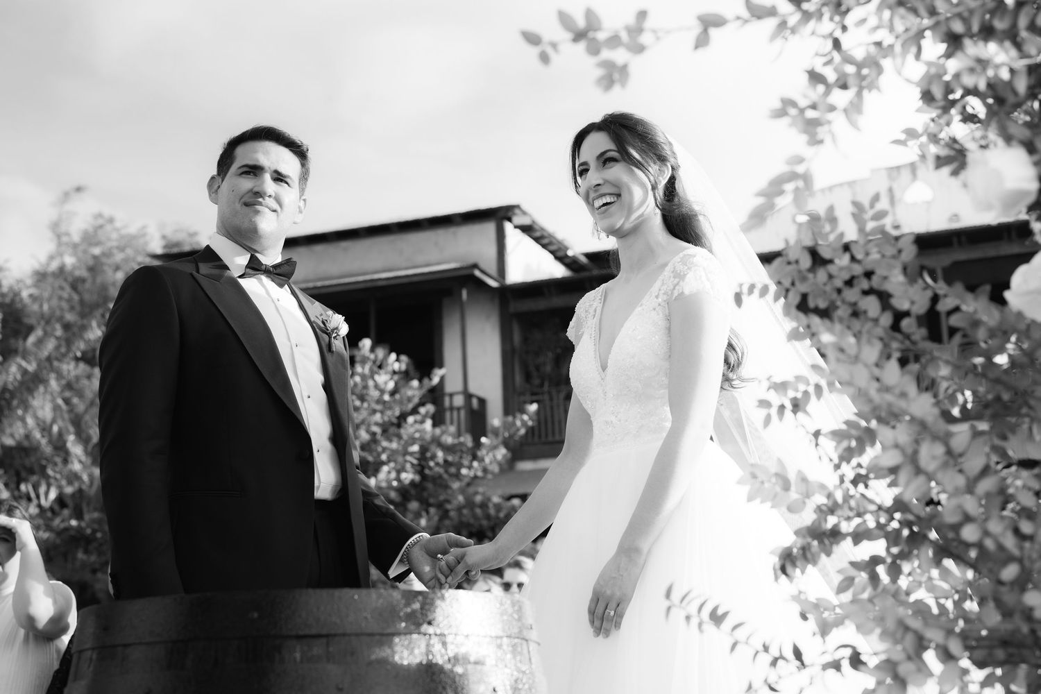 A black and white wedding photo showing an intimate outdoor ceremony moment.