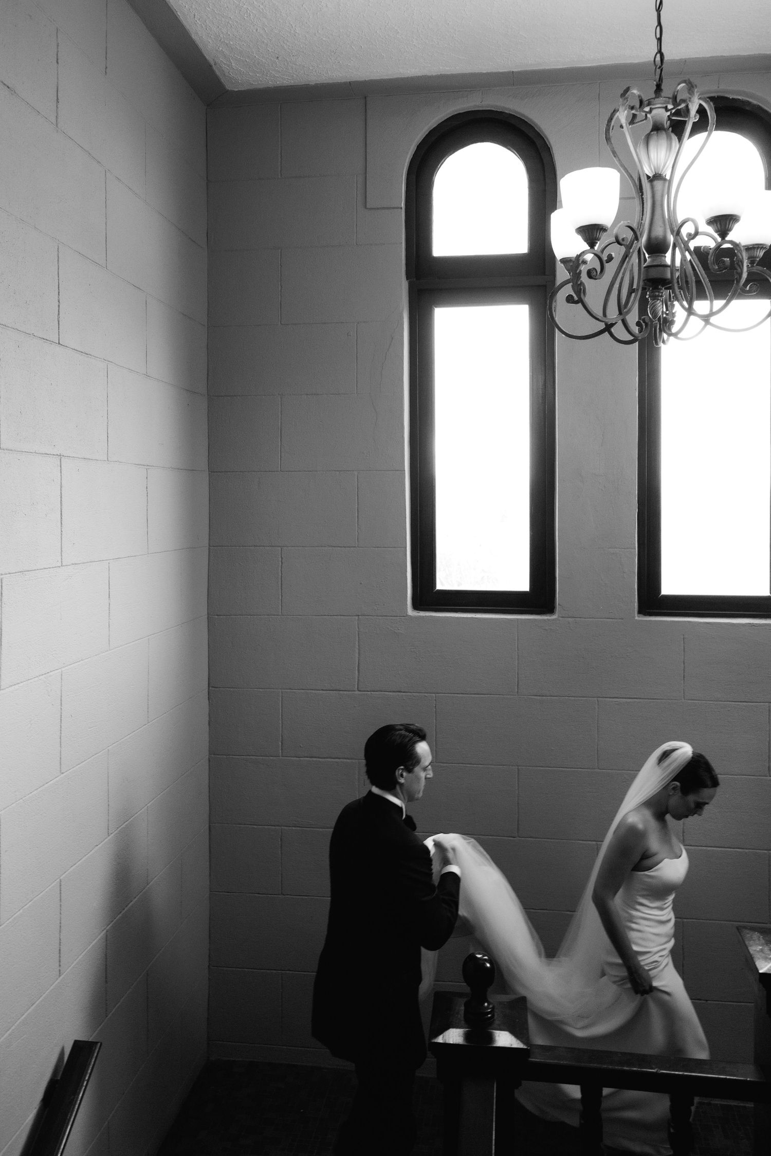 Black and white artistic sequence showing solitude in a room with arched windows and chandelier.