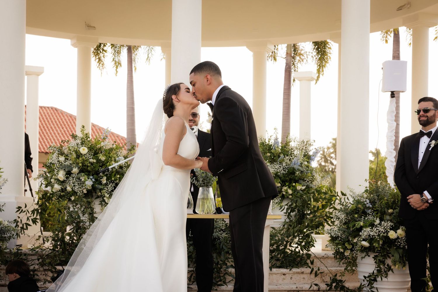 A black and white photo series of a romantic outdoor wedding ceremony with a bride and groom under a columned walkway.