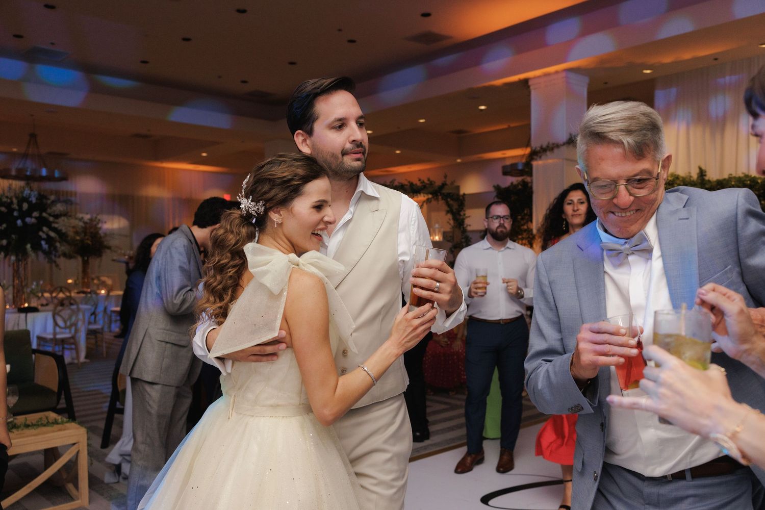Couple sharing a dance together at an evening reception with warm lighting and other guests in the background.