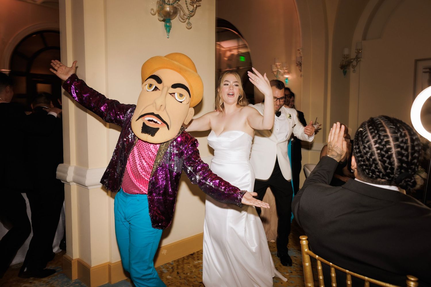 Wedding guests dancing and celebrating energetically on a dimly lit dance floor.