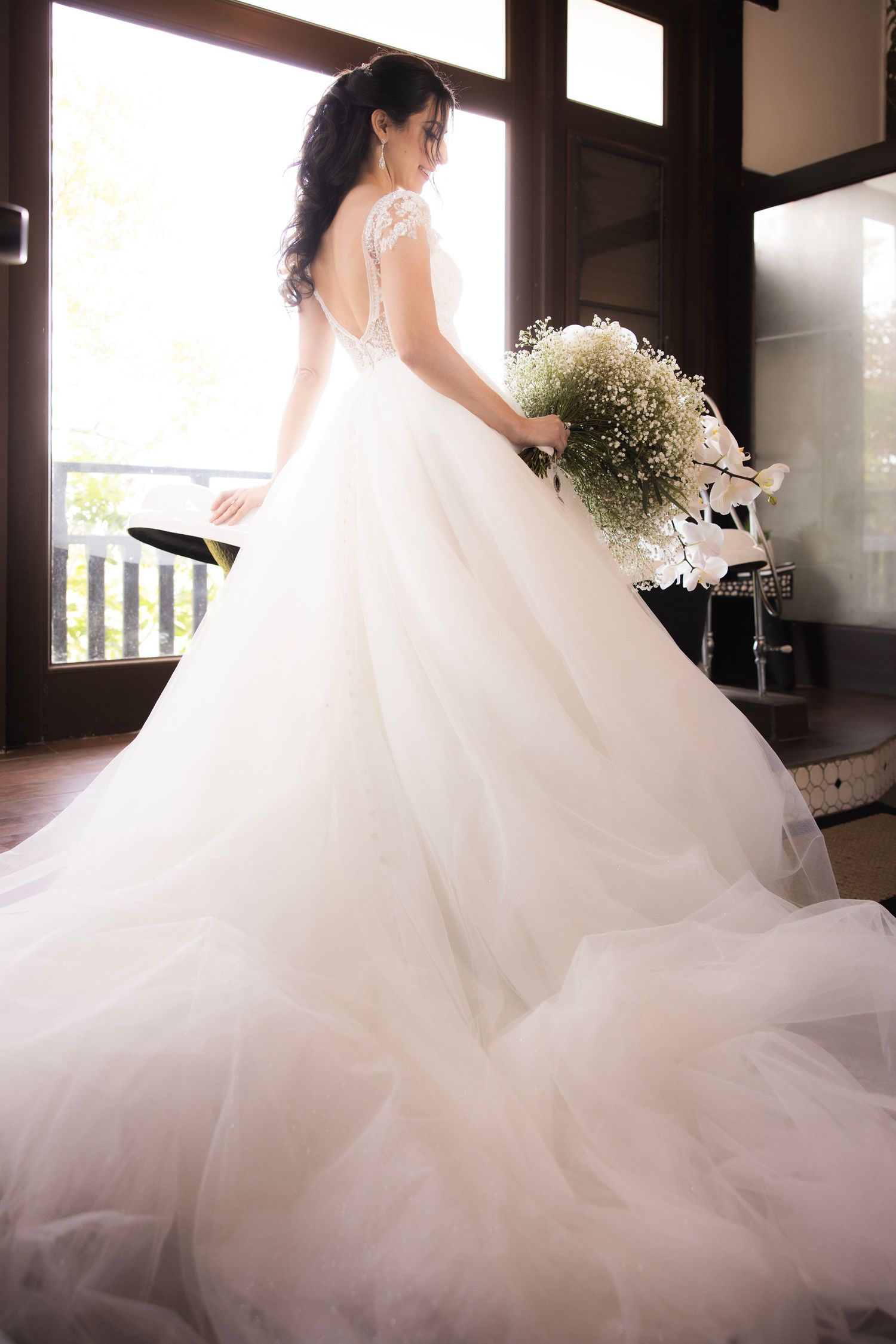 Close-up view of a romantic white wedding dress with delicate lace details and flowing tulle layers.