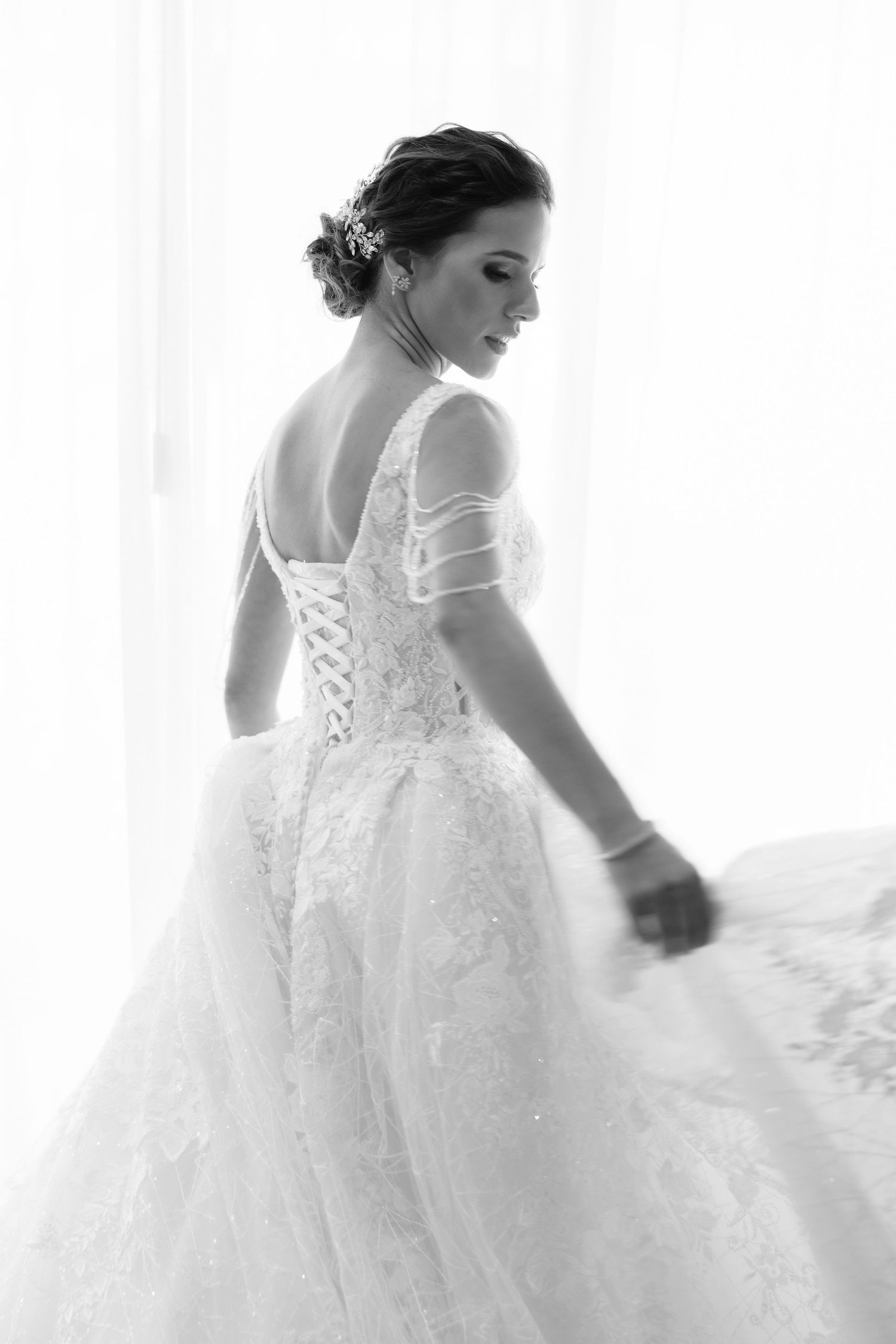 Bride in a flowing white lace wedding dress spins gracefully showing the elegant back details of her gown.