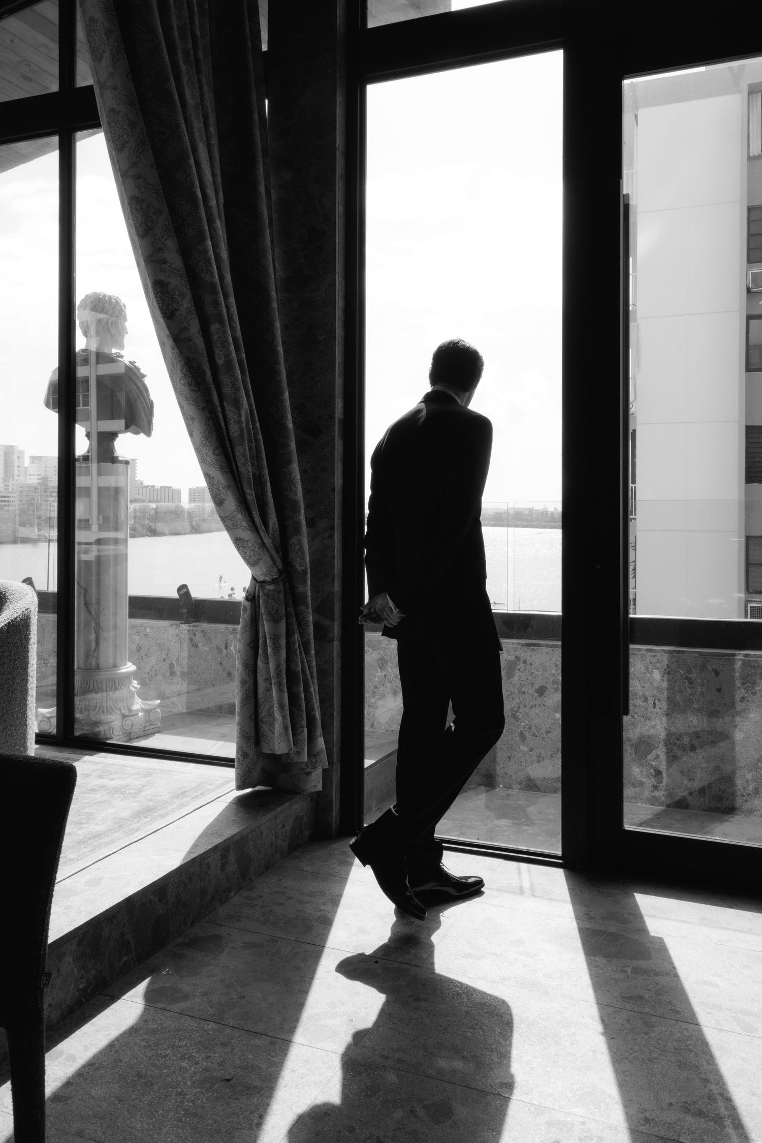 Silhouettes of people standing near large windows cast dramatic shadows across the floor in a sequence of black and white photos.