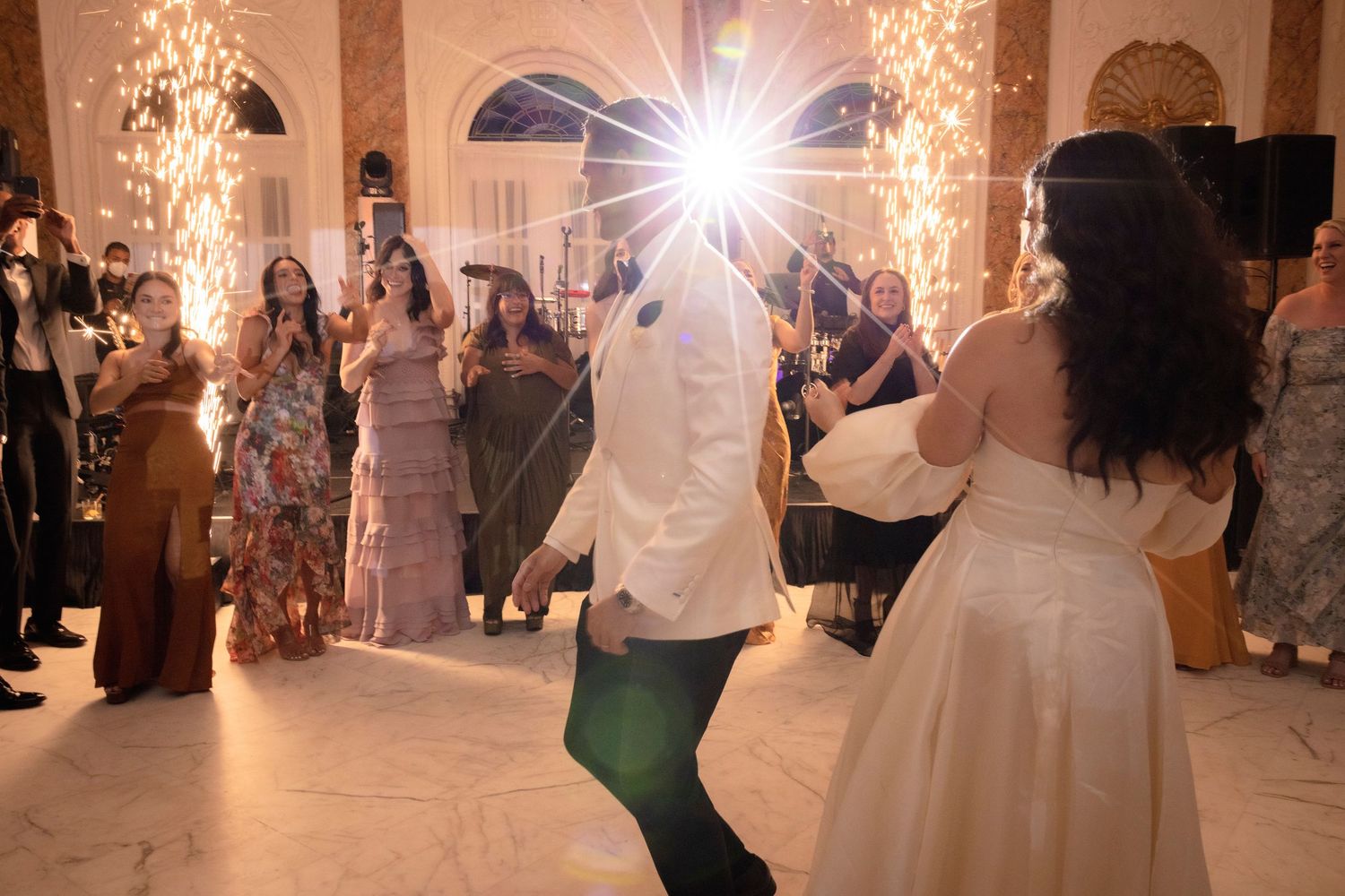 Wedding guests dance and celebrate on an illuminated dance floor at an elegant reception venue.